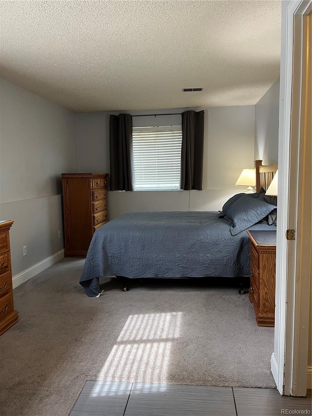 bedroom featuring a textured ceiling, carpet floors, and baseboards