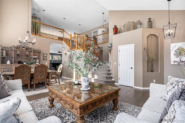 living room featuring a notable chandelier, high vaulted ceiling, stairs, and wood finished floors