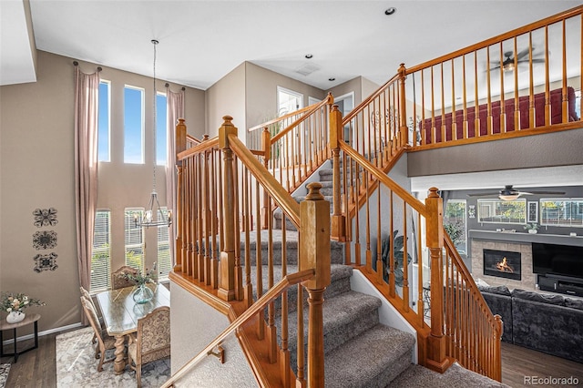 stairway featuring a high ceiling, wood finished floors, and a tile fireplace