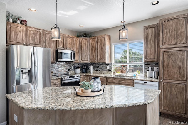 kitchen featuring light stone countertops, a kitchen island, a sink, stainless steel appliances, and tasteful backsplash