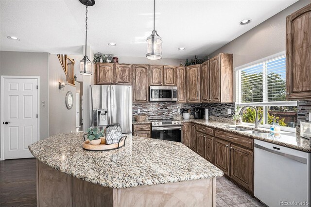 kitchen featuring tasteful backsplash, stainless steel appliances, light stone counters, and a sink