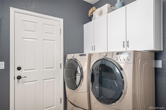 laundry room featuring a textured wall, cabinet space, and washer and clothes dryer