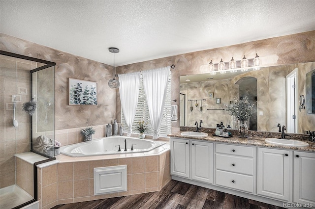 full bath featuring a sink, a textured ceiling, and a stall shower