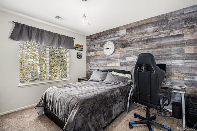 carpeted bedroom with an accent wall, wooden walls, baseboards, and visible vents