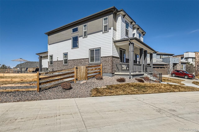 view of side of home featuring fence and covered porch