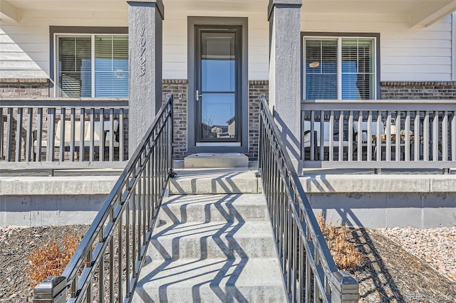 property entrance with brick siding and a porch