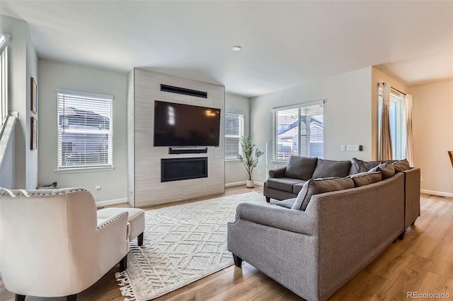 living room with light wood finished floors, a large fireplace, and baseboards