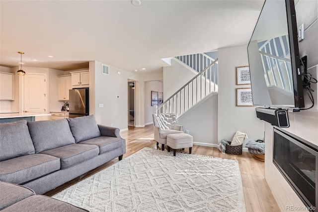 living area featuring recessed lighting, visible vents, stairs, and light wood finished floors