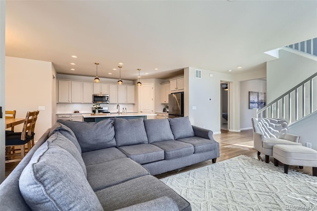 living area with stairway, recessed lighting, visible vents, and light wood-type flooring