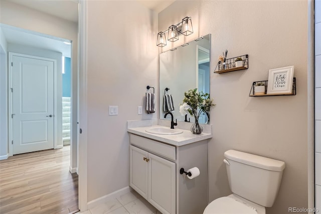 bathroom featuring baseboards, toilet, and vanity