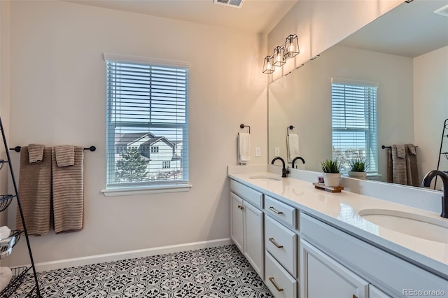 full bath with tile patterned flooring, double vanity, baseboards, and a sink