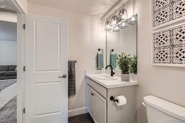 half bathroom with tile patterned flooring, toilet, and vanity