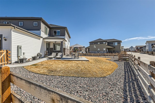 back of property with a fenced backyard, a residential view, and a patio