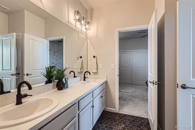 bathroom featuring a sink, visible vents, baseboards, and double vanity