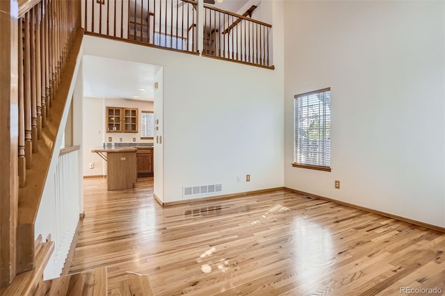 unfurnished living room featuring light hardwood / wood-style flooring and a high ceiling