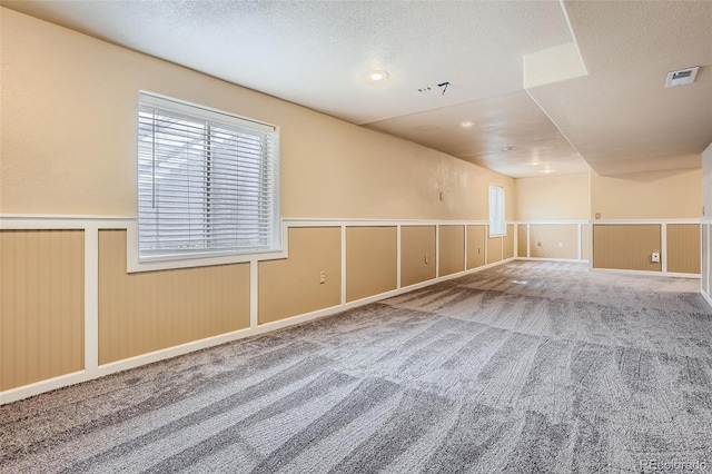 carpeted empty room featuring a healthy amount of sunlight and a textured ceiling