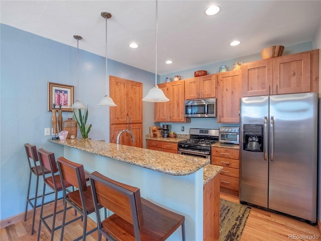 1033 H St, Salida, CO 81201 - kitchen with stainless steel appliances, a breakfast bar, light wood-style flooring, a peninsula, and hanging light fixtures