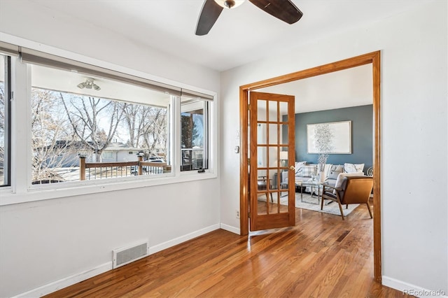 interior space with baseboards, visible vents, ceiling fan, wood finished floors, and french doors