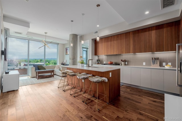 4200 W 17th Ave Unit 625, Denver, CO 80204 - kitchen with modern cabinets, a kitchen breakfast bar, wood-type flooring, tasteful backsplash, and a center island with sink