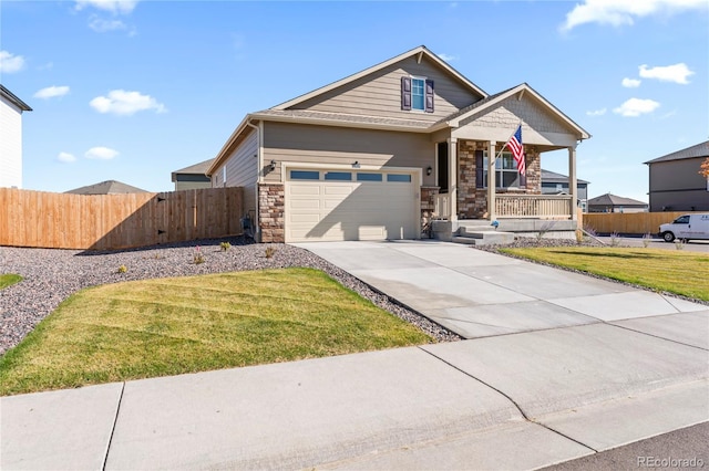 view of front of home with driveway, stone siding, fence, a porch, and a front yard