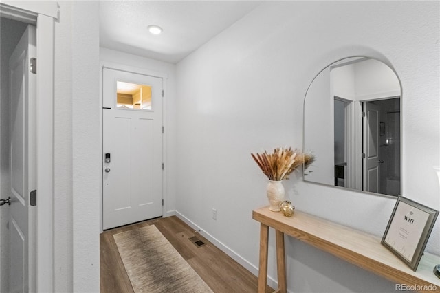 foyer featuring visible vents, baseboards, and wood finished floors