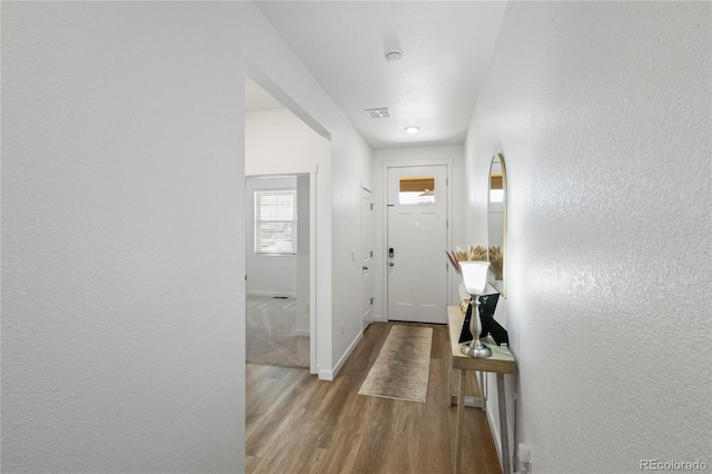 entryway featuring visible vents, baseboards, wood finished floors, and a textured wall