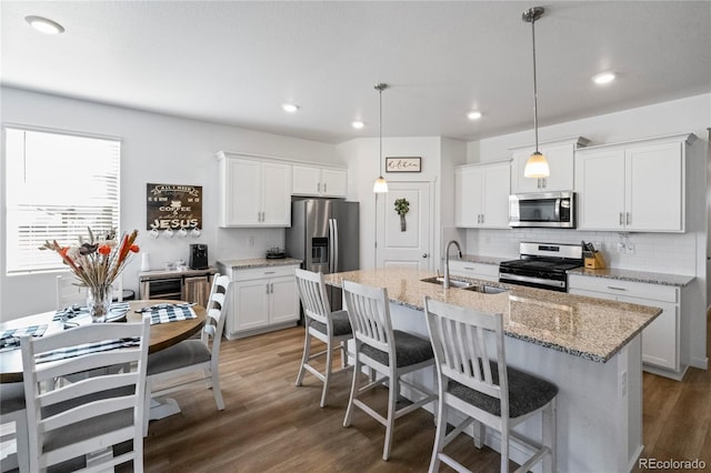 kitchen with stainless steel appliances, a breakfast bar, a sink, and wood finished floors