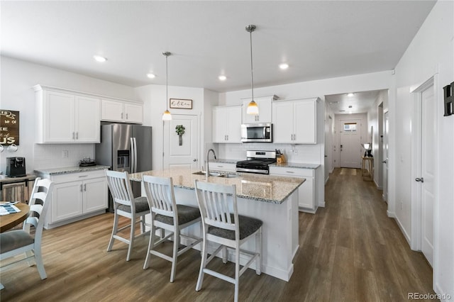 kitchen with appliances with stainless steel finishes, dark wood-type flooring, a center island with sink, and white cabinets