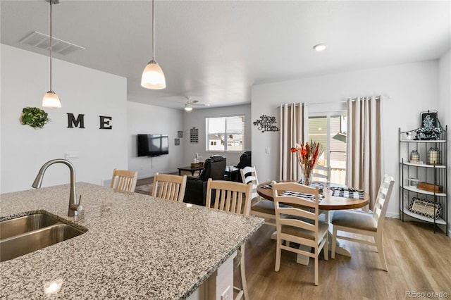 kitchen with pendant lighting, visible vents, a sink, ceiling fan, and light wood-type flooring