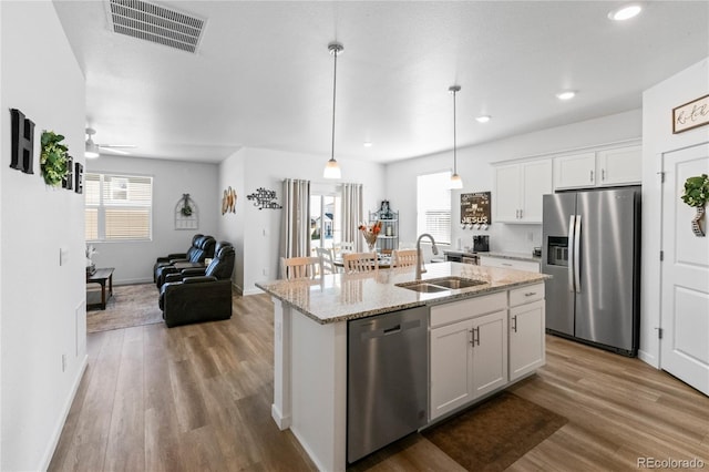 kitchen with stainless steel appliances, wood finished floors, a sink, visible vents, and open floor plan