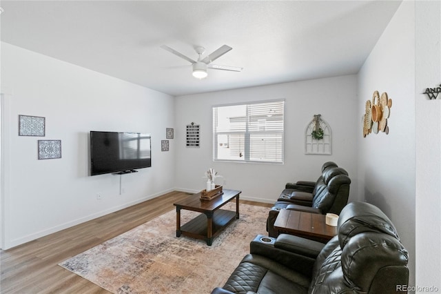 living area featuring a ceiling fan, baseboards, and wood finished floors