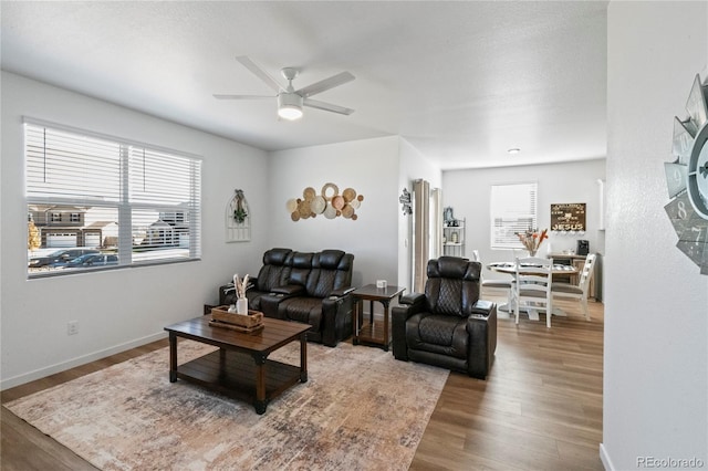 living room with wood finished floors, a ceiling fan, and baseboards