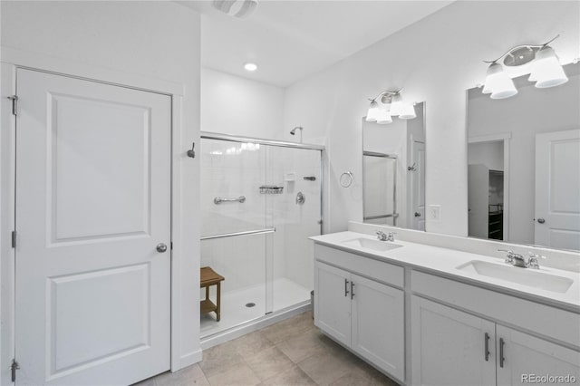 full bath with double vanity, a shower stall, a sink, and tile patterned floors