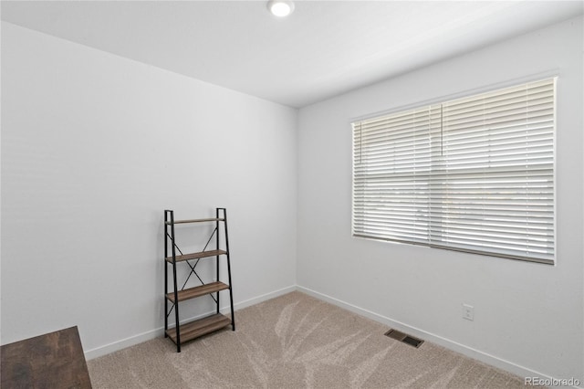 carpeted empty room featuring visible vents and baseboards