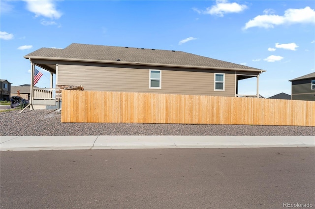 view of property exterior with roof with shingles and fence