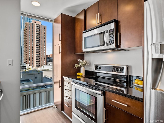 kitchen with light hardwood / wood-style floors, appliances with stainless steel finishes, and dark stone counters