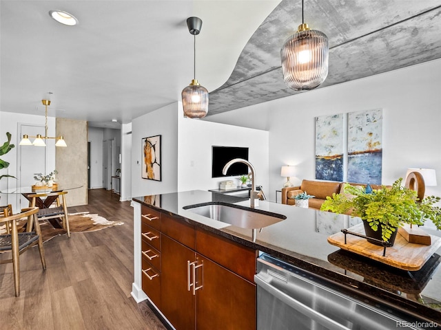 kitchen featuring stainless steel dishwasher, sink, dark wood-type flooring, and hanging light fixtures