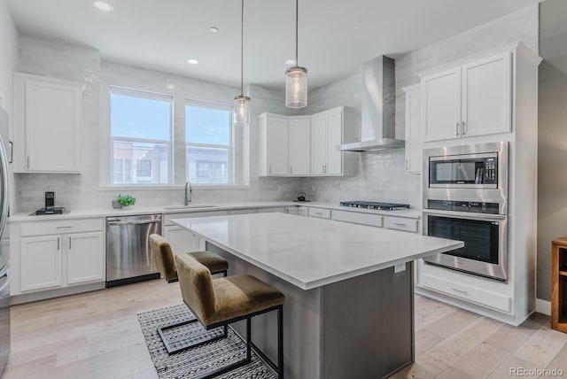 2282 Old Rail Way, Superior, CO 80027 - kitchen featuring appliances with stainless steel finishes, wall chimney range hood, light wood-style floors, white cabinetry, and recessed lighting