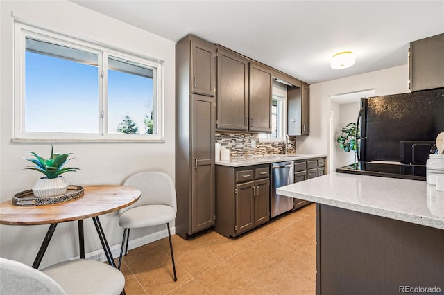 kitchen featuring baseboards, light tile patterned flooring, freestanding refrigerator, decorative backsplash, and stainless steel dishwasher