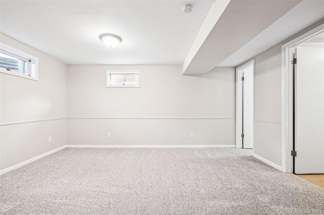 basement with a wealth of natural light, light colored carpet, and baseboards