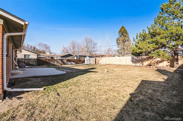 view of yard with an outdoor structure, a fenced backyard, a shed, and a patio area