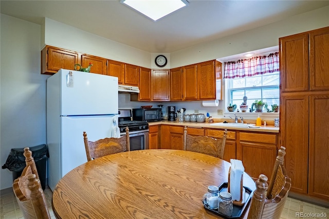 4115 S Clarkson St, Englewood, CO 80113 - kitchen with a sink, stainless steel gas stove, light countertops, under cabinet range hood, and freestanding refrigerator