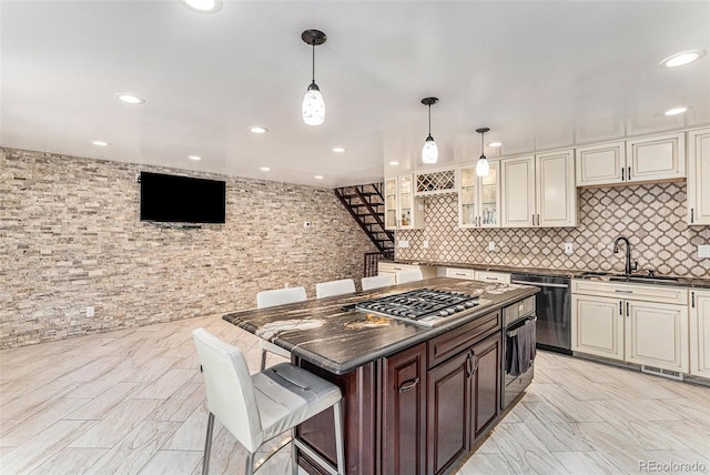 kitchen featuring a kitchen island, pendant lighting, stainless steel appliances, a kitchen bar, and sink