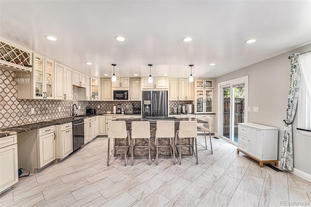 kitchen featuring cream cabinets, a breakfast bar area, decorative light fixtures, and black appliances