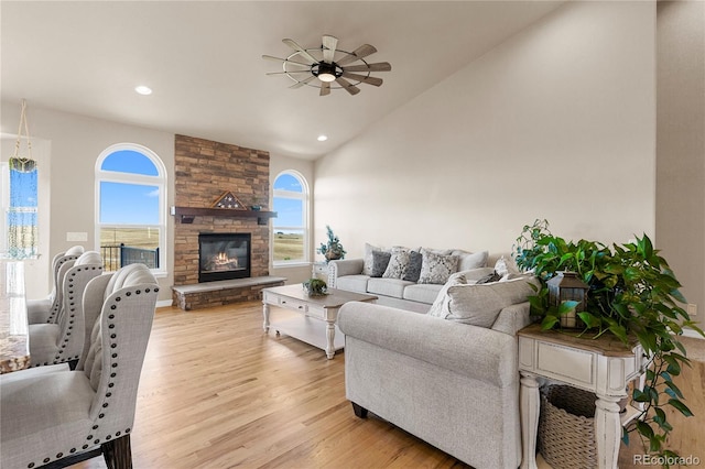 living room with lofted ceiling, a fireplace, light hardwood / wood-style floors, and ceiling fan