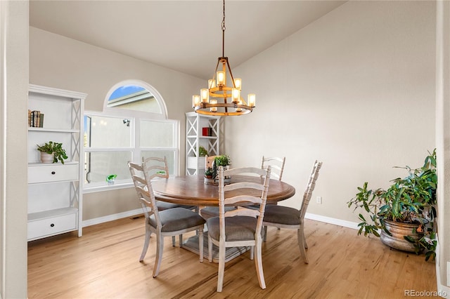 dining area with lofted ceiling, a notable chandelier, and light hardwood / wood-style floors