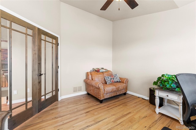 sitting room with french doors, light wood-type flooring, and ceiling fan