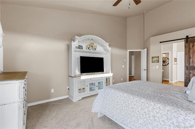 bedroom featuring ceiling fan, light carpet, a high ceiling, and a barn door