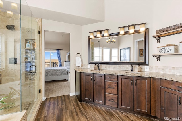 bathroom featuring vanity, an enclosed shower, wood-type flooring, and an inviting chandelier