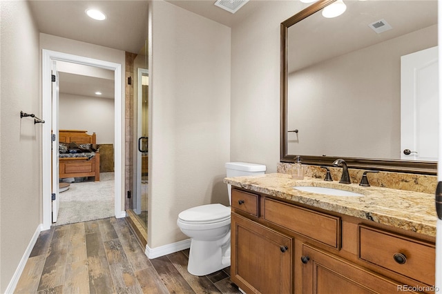 bathroom featuring vanity, walk in shower, hardwood / wood-style flooring, and toilet